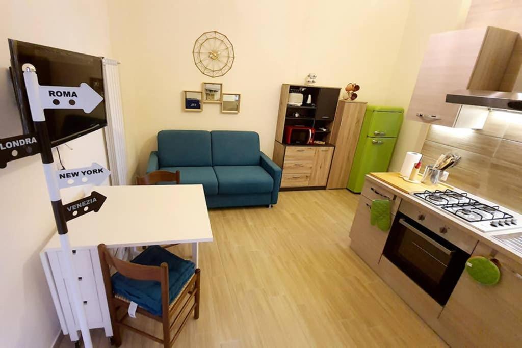 Il comprend une petite cuisine et un salon avec un canapé bleu. dans l'établissement Casa Cerasella: Beautiful apartment in the city center of Minturno, à Minturno