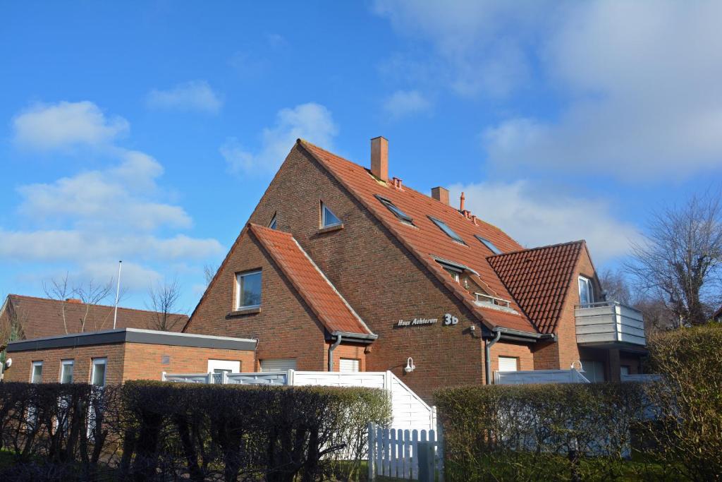 une grande maison en briques avec un toit rouge dans l'établissement Haus Achterum, à Langeoog