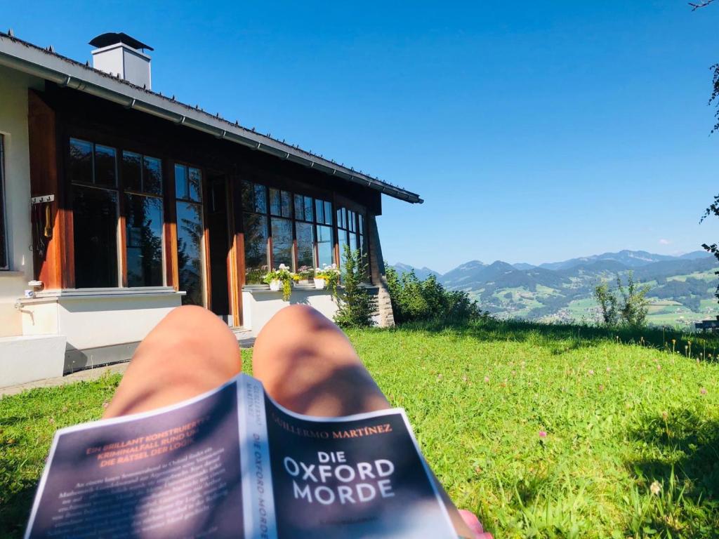 a person reading a book in front of a house at Ferienhaus Mätzler in Schwarzenberg