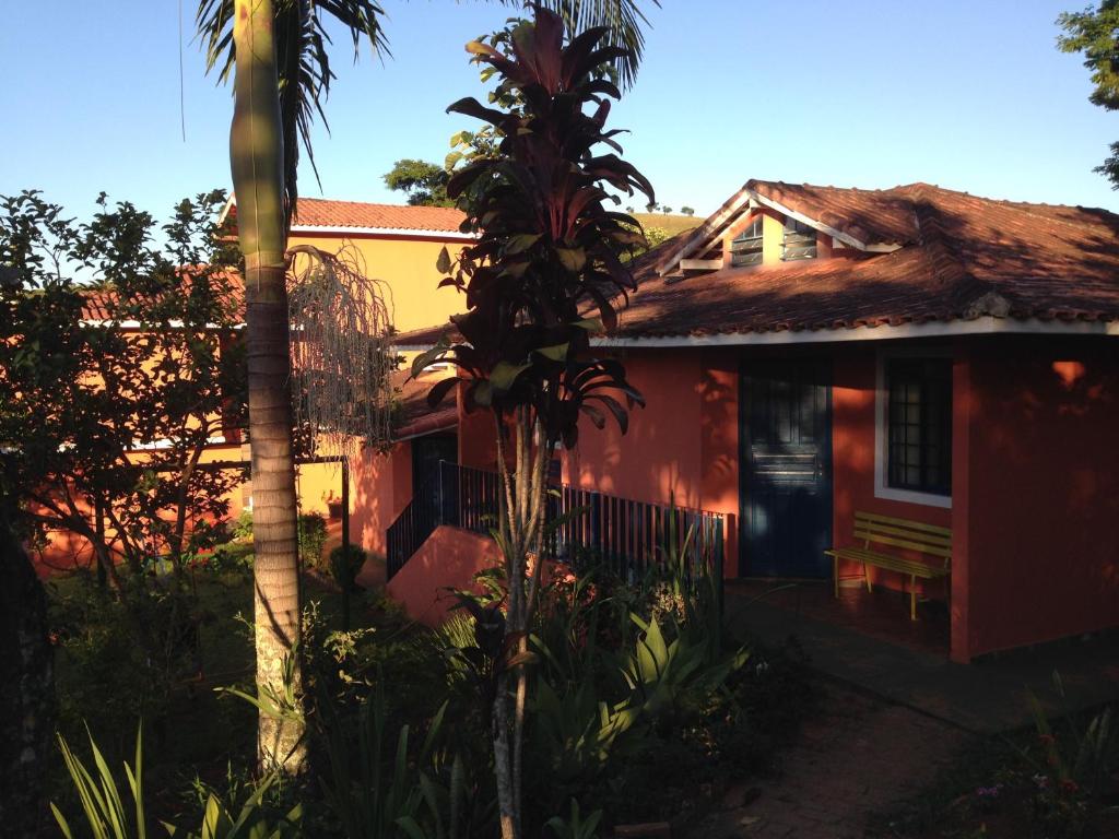 a red house with a palm tree in front of it at Pousada Vista Verde in Cunha