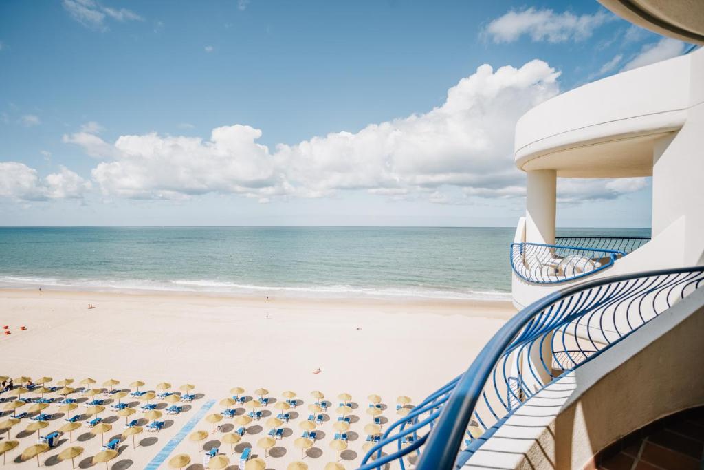 een balkon met uitzicht op het strand bij Hotel Playa Victoria in Cádiz