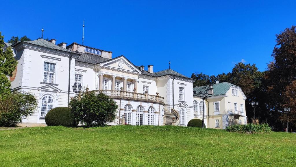 una grande casa bianca in cima a una collina erbosa di Pokoje Gościnne Pałac w Balicach Instytut Zootechniki PIB a Balice