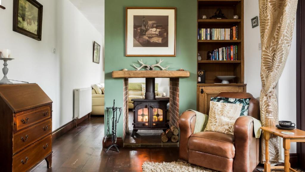 a living room with a fireplace and a chair at The Willows in Christchurch