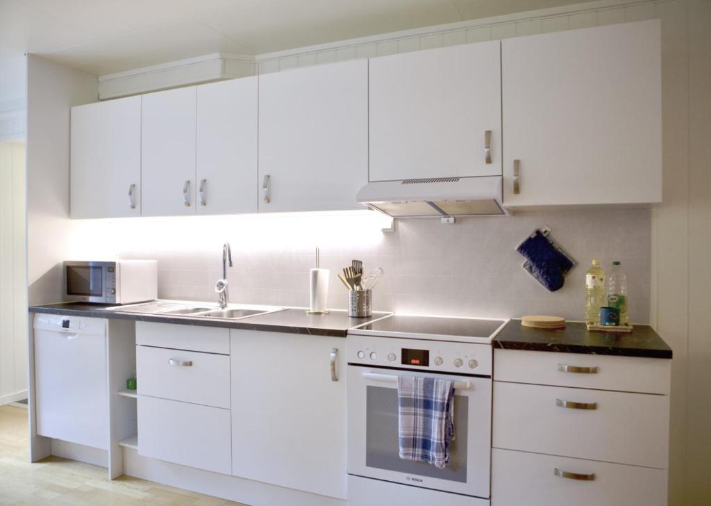 a white kitchen with white cabinets and a sink at Modern apartment in Svolvær