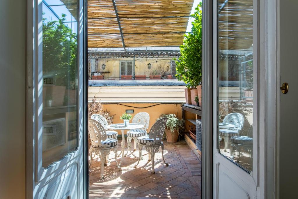 une porte menant à une terrasse avec une table et des chaises. dans l'établissement Frattina Apartments, à Rome