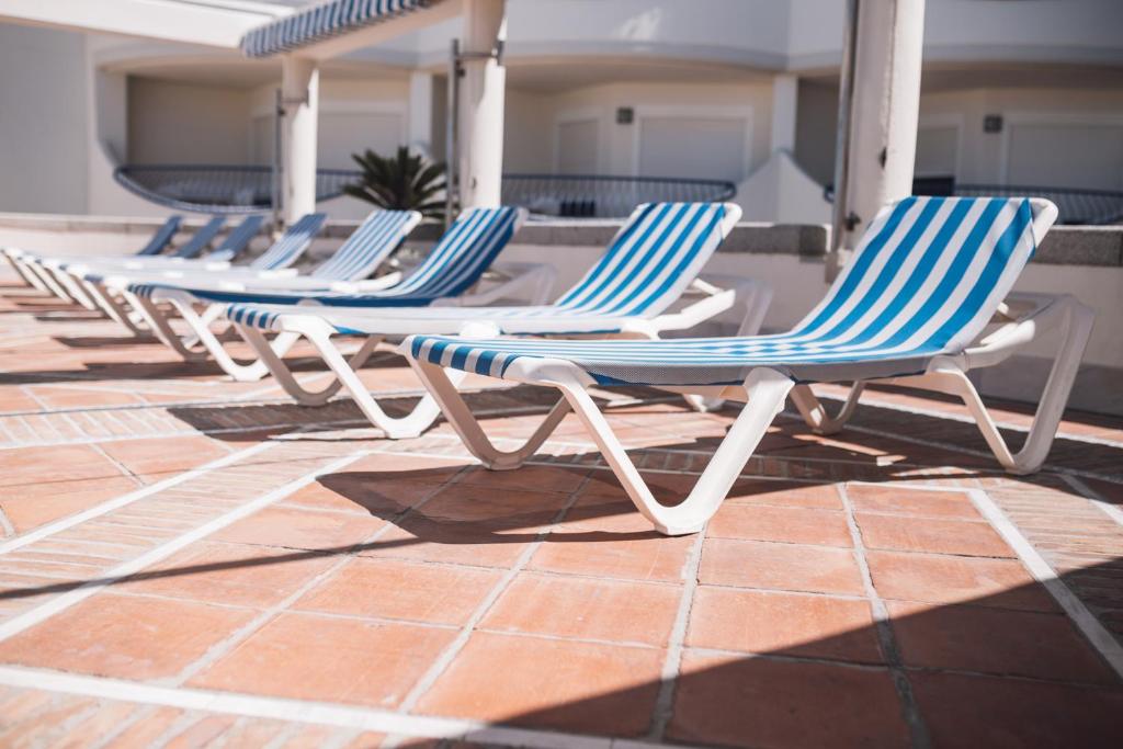 a row of blue and white chairs on a patio at Hotel Playa Victoria in Cádiz
