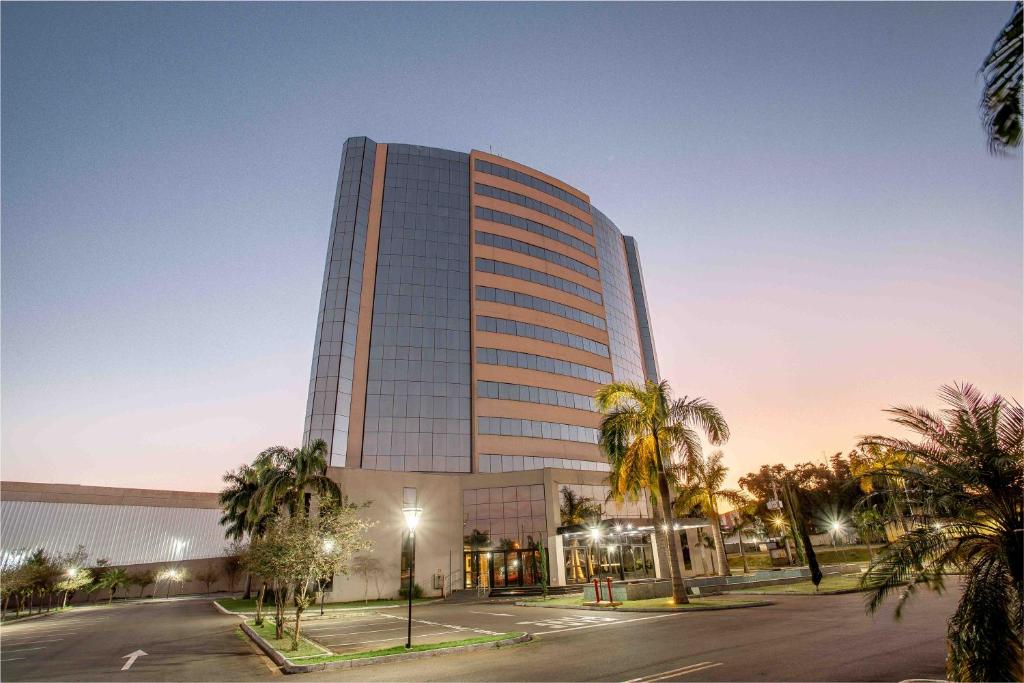 a tall building with palm trees in front of it at Zahara Hotel in Limeira