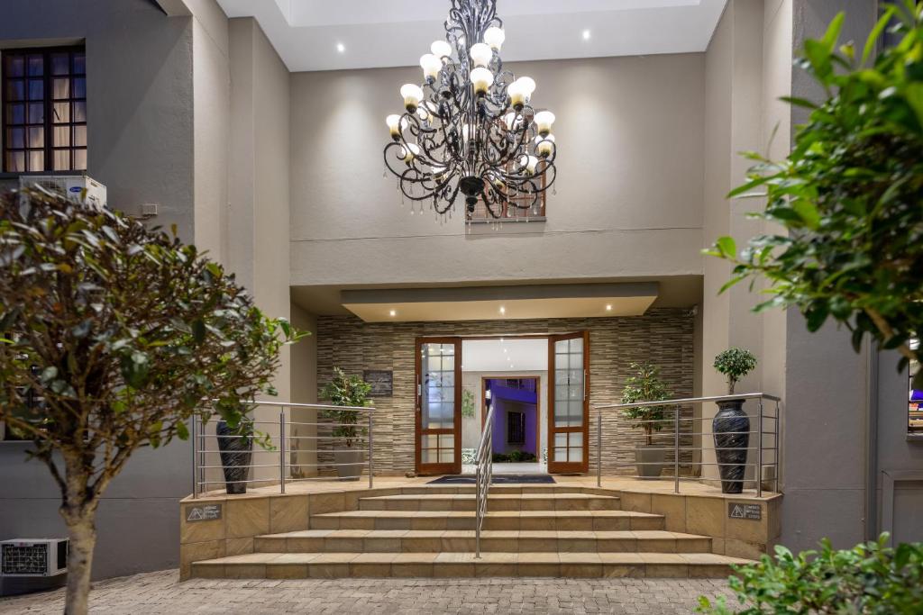 eine große Lobby mit Treppen und einem Kronleuchter in der Unterkunft The Cycad Lodge & Chalets in Nelspruit