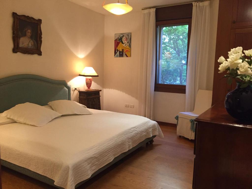 ein Schlafzimmer mit einem Bett und einer Vase aus Blumen in der Unterkunft Villa Liberty in Lido di Venezia