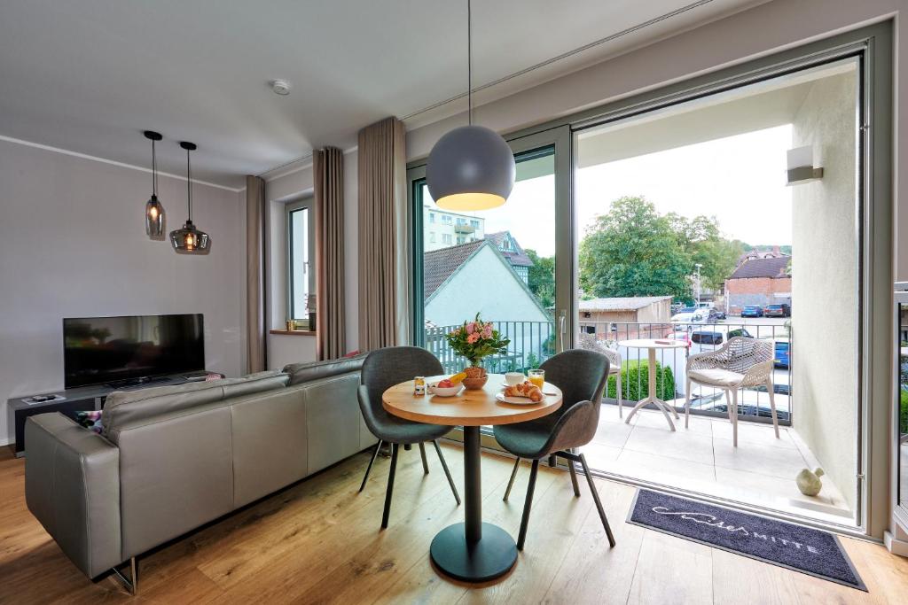 a living room with a table and chairs and a television at Suites MITTE - Aparthotel in Eisenach