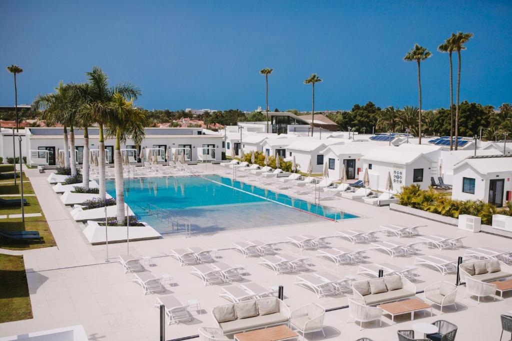 - une piscine avec des chaises longues et un complexe dans l'établissement Club Maspalomas Suites & Spa - Adults Only, à Maspalomas