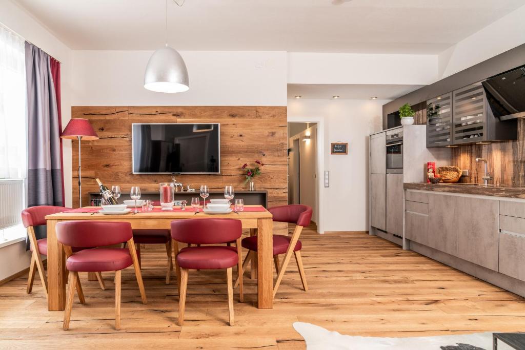 a kitchen and dining room with a wooden table and red chairs at Apartments Greisslerei in Aich