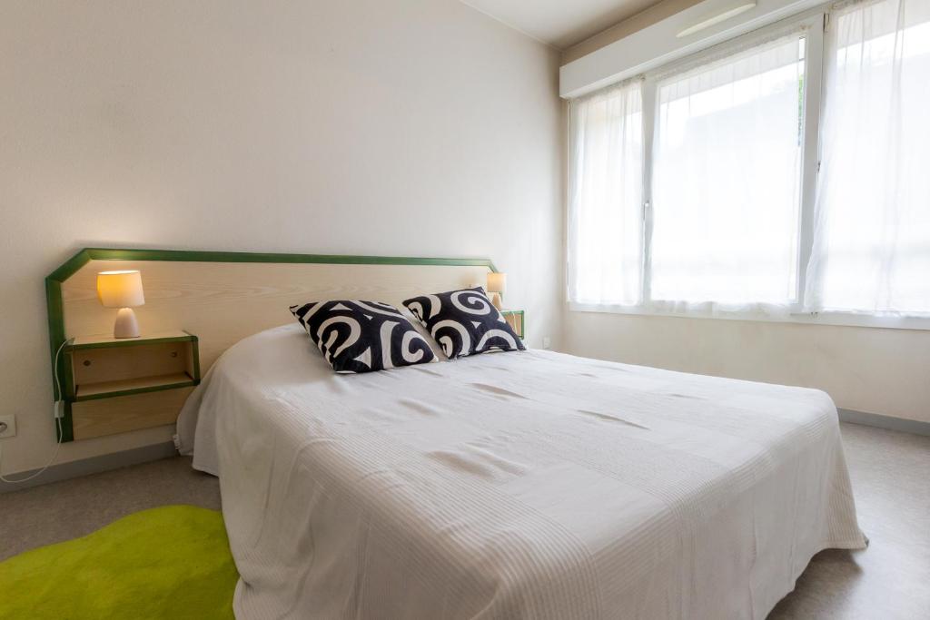 Un dormitorio con una gran cama blanca con almohadas. en Sphinx Résidences - Les Germes de Blé, en Épron