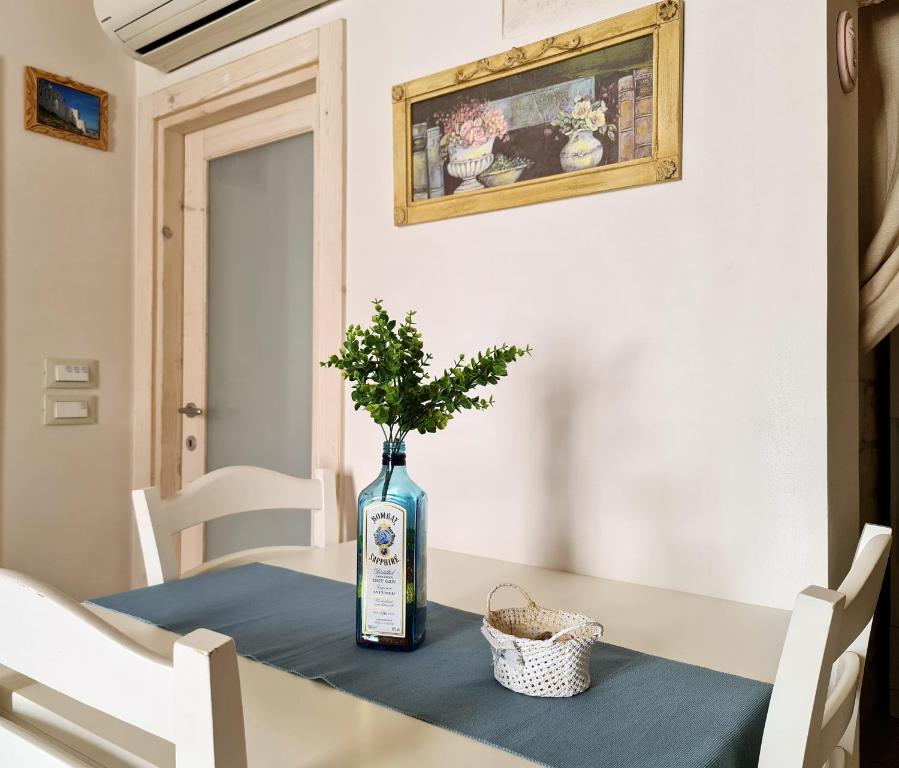 uma mesa com uma garrafa e uma planta sobre ela em BiancoAmore OSTUNI - the sky, the sea, the love - em Ostuni