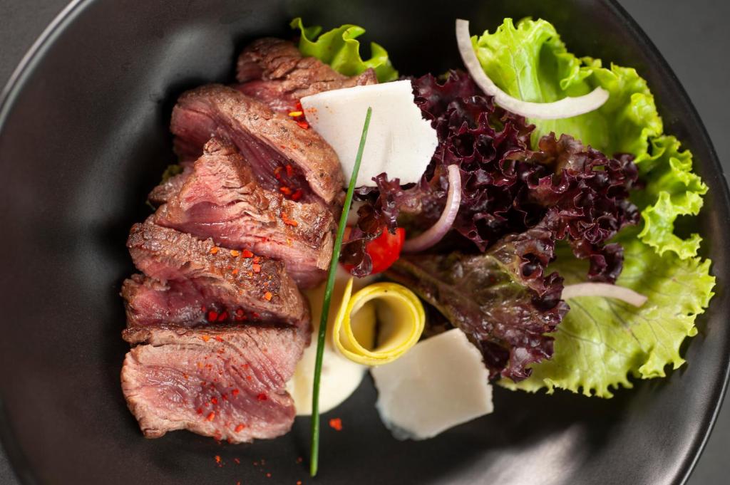 a plate of food with meat and a salad at Vivid Blue Serenity Resort in Sveti Stefan