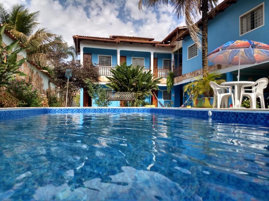 a villa with a swimming pool in front of a house at POUSADA CARVALHO in Pirenópolis