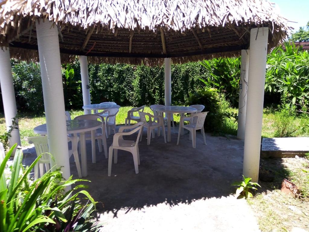 un grupo de mesas y sillas bajo una sombrilla de paja en Villa kosniin en Tecolutla