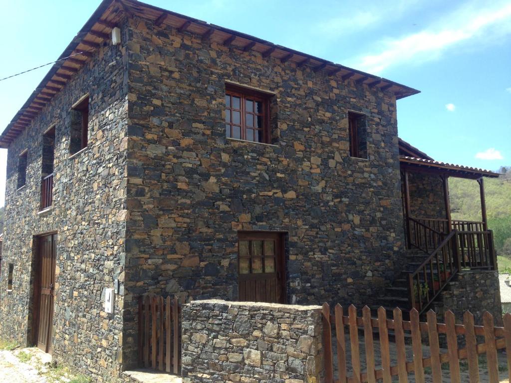 a stone house with a fence in front of it at Casa do Rebelhe in Bragança