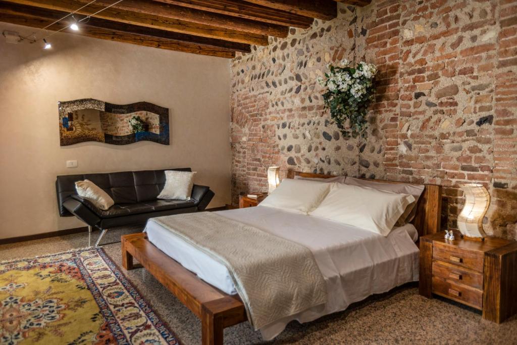 ヴェローナにあるLa Bella Verona Wine Suiteのレンガの壁のベッドルーム1室、ベッド1台、椅子1脚が備わります。