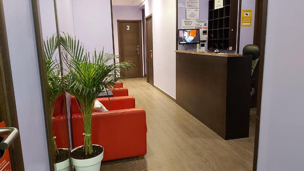 un pasillo de oficinas con dos sillas rojas y plantas en Hostal Corazón de Madrid, en Madrid