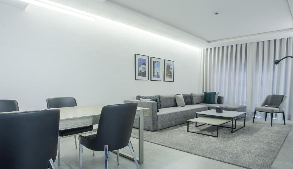 Makass Appart Hotel في الرباط: غرفة معيشة مع أريكة وطاولة وكراسي