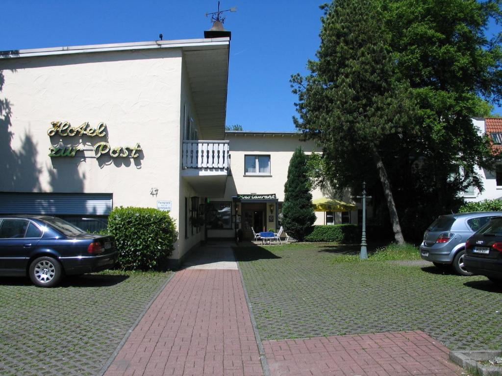 a building with cars parked in a parking lot at Hotel Restaurant zur Post in Wuppertal