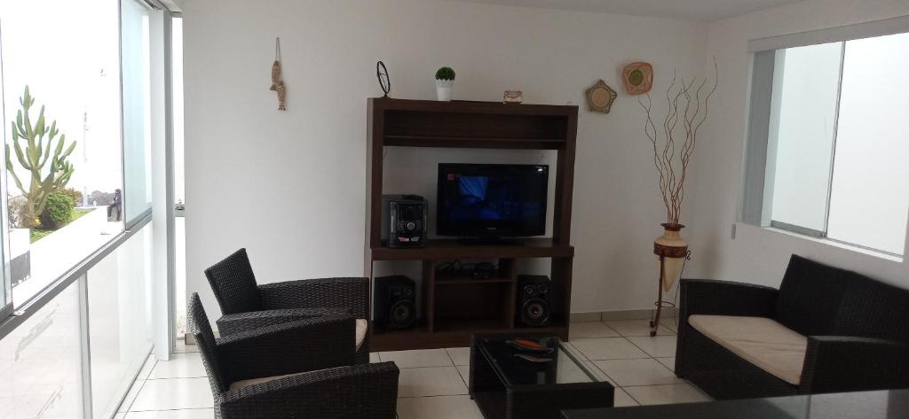 sala de estar con TV y 2 sillas en Departamentos en Playa La Isla, en Punta Hermosa