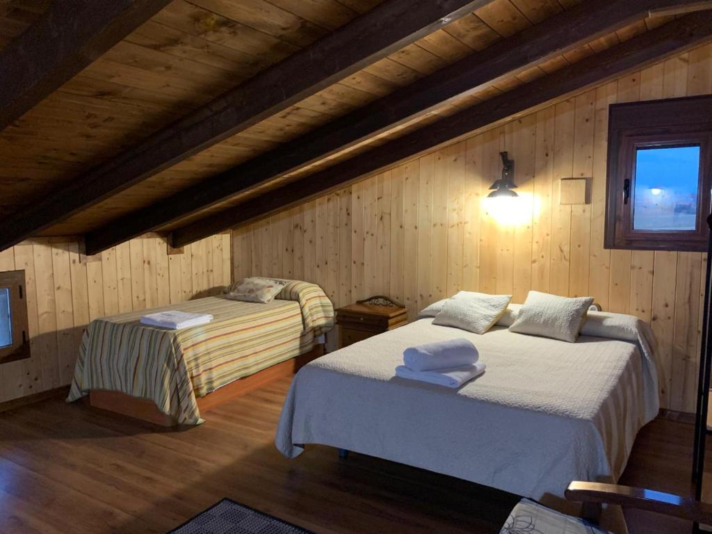two beds in a room with wooden walls at Casa rural Alcala Cabaña Del herrero in Alcalá del Júcar