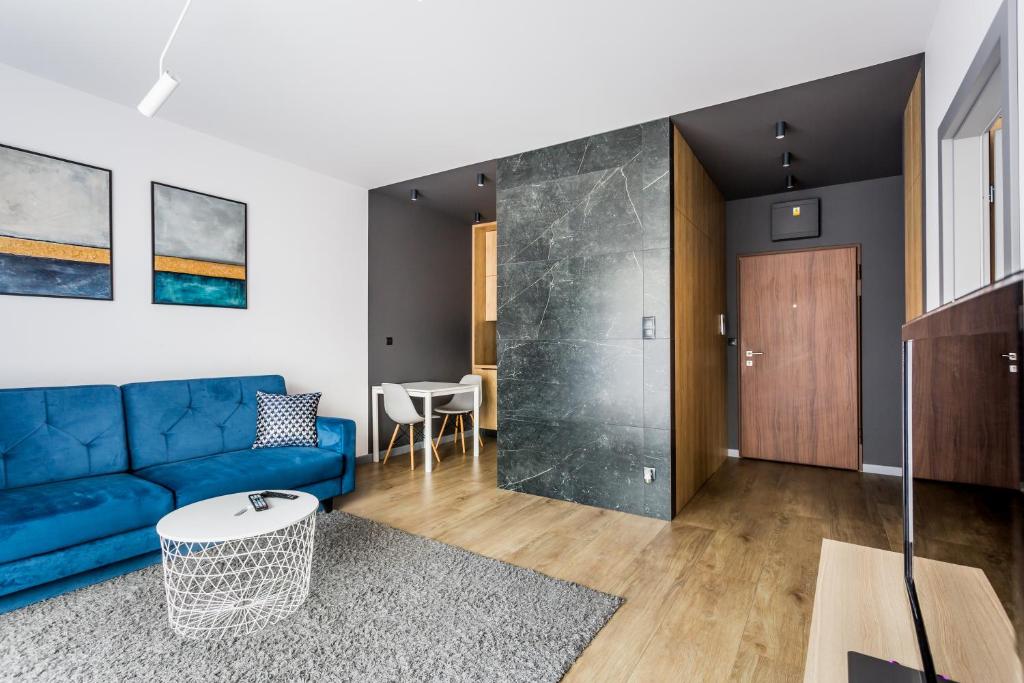 - un salon avec un canapé bleu et une table dans l'établissement ResiNest Apartamenty Butikowa Kamienica M40, à Białystok