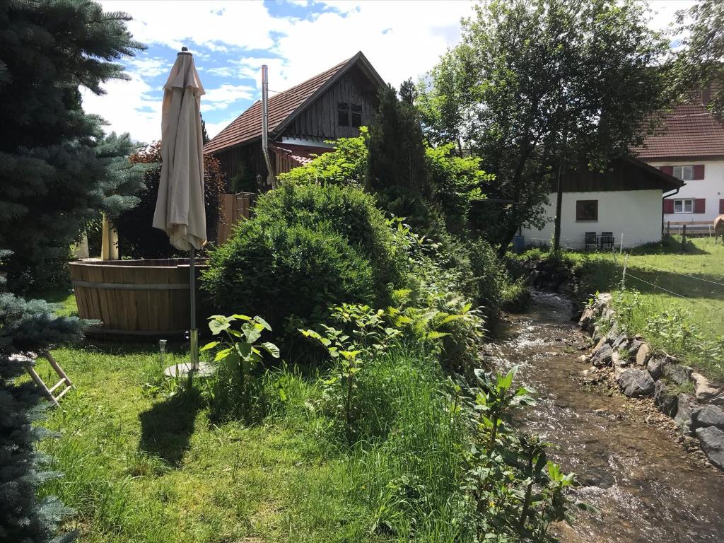 a garden with an umbrella and a tub in front of a house at Die Dirndlkönigin in Grünenbach
