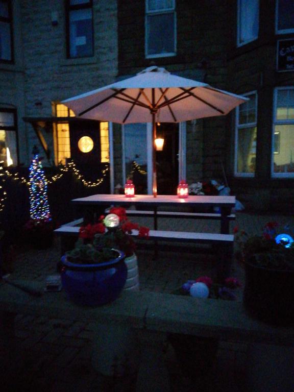 a picnic table with an umbrella in front of a house at Captains Lodge in Newbiggin-by-the-Sea