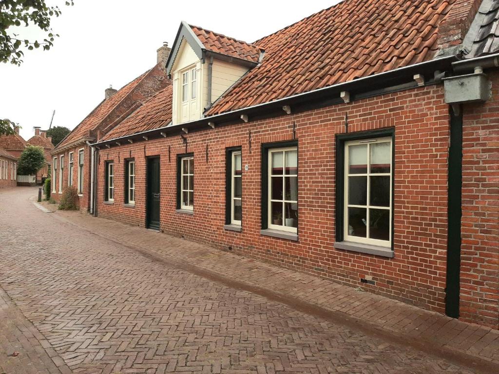 a brick building with windows on a street at Winsum - Groningen - 6 pers. Cosy Cottage - Op en Bie t Woater in Winsum
