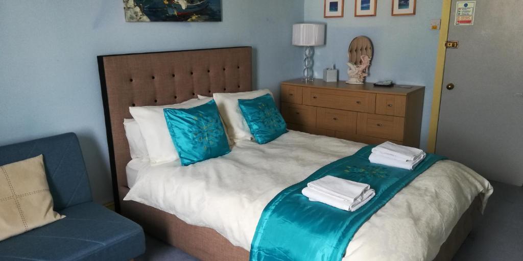 Un dormitorio con una cama con almohadas azules y una silla azul. en Northdene Theatre Hotel en Blackpool