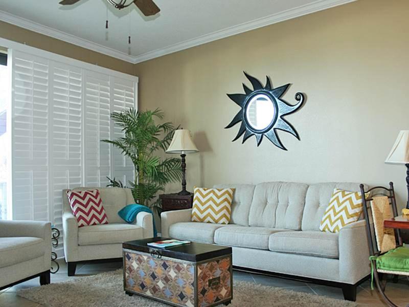 a living room with a couch and a sun on the wall at Mainsail I in Destin