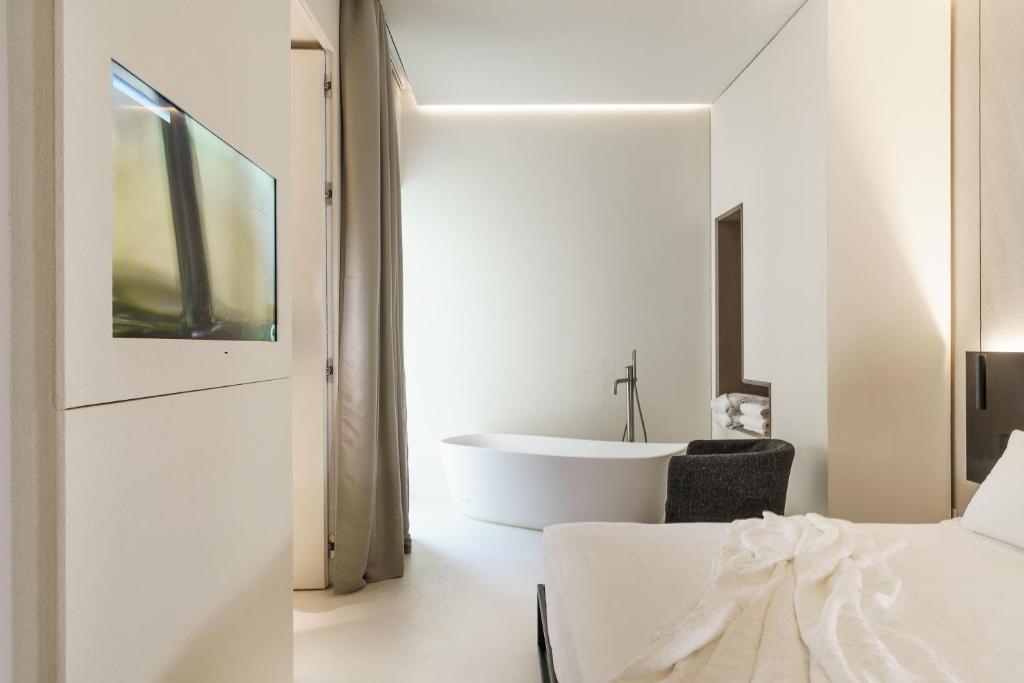 a white bathroom with a tub and a bed at Meo Design Suites & Spa in Catania