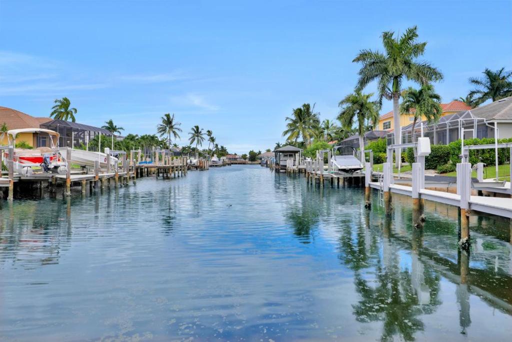 a canal with boats and houses and palm trees at Waterfront home with pool and foosball table in Marco Island