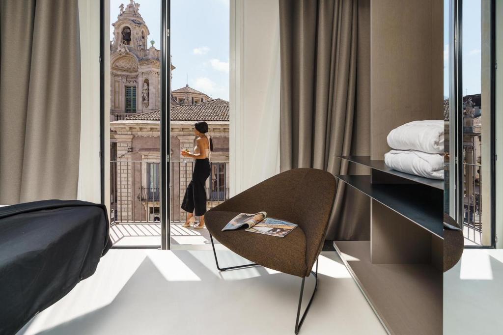 a woman looking out the window of a hotel room at Meo Design Suites & Spa in Catania