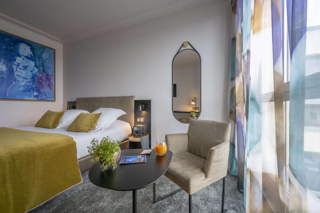 a hotel room with a bed, chair, and table at Best Western Premier Masqhotel in La Rochelle
