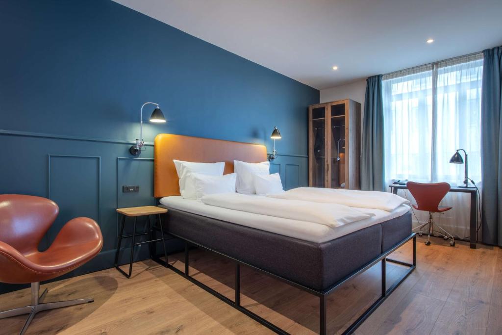 - une chambre avec un grand lit et un mur bleu dans l'établissement The Huxley Copenhagen, BW Premier Collection, à Copenhague
