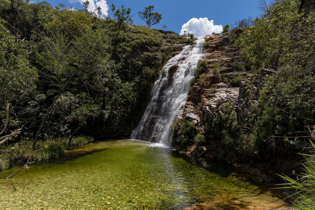 uma cascata com uma piscina de água em frente em Pousada Cachoeira Lagoa Azul em Capitólio