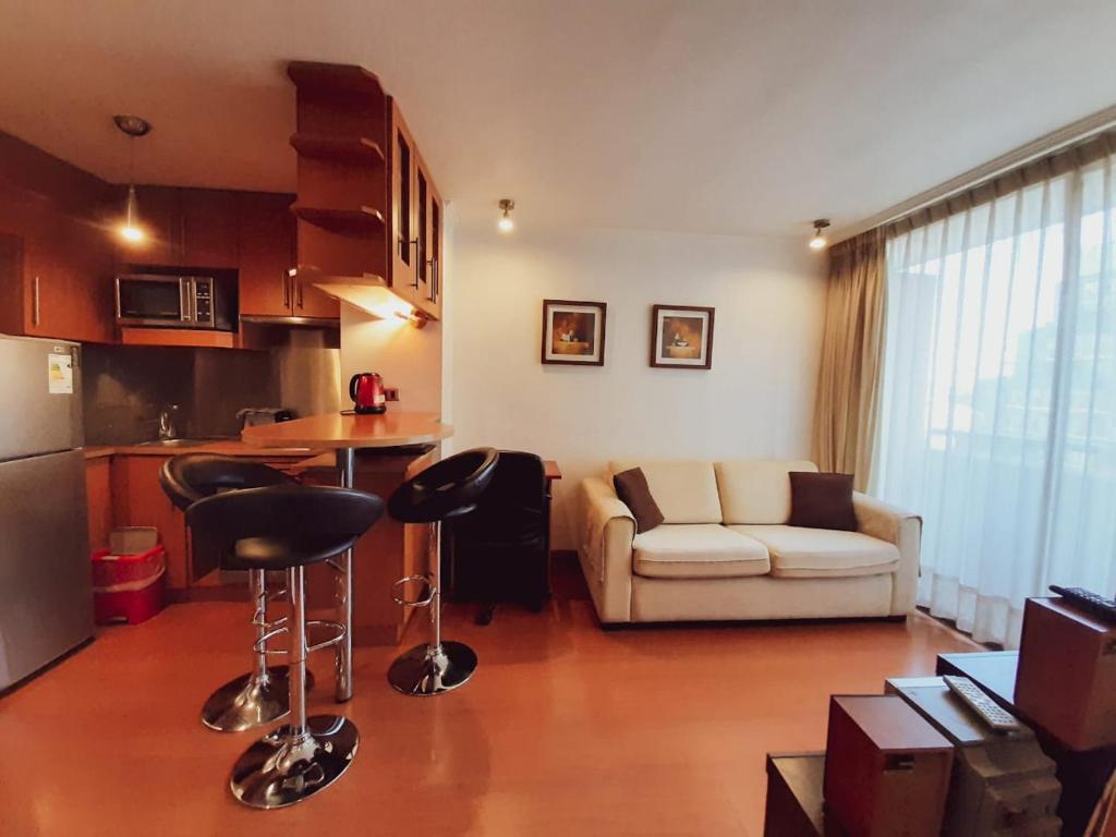 Ram Apartamentos في سانتياغو: مطبخ وغرفة معيشة مع أريكة وطاولة