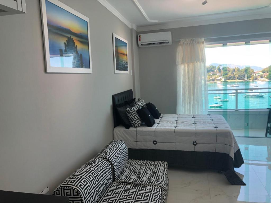Un dormitorio con una cama y un sofá y una ventana. en Flat Angra Inn, Angra dos Reis, en Angra dos Reis