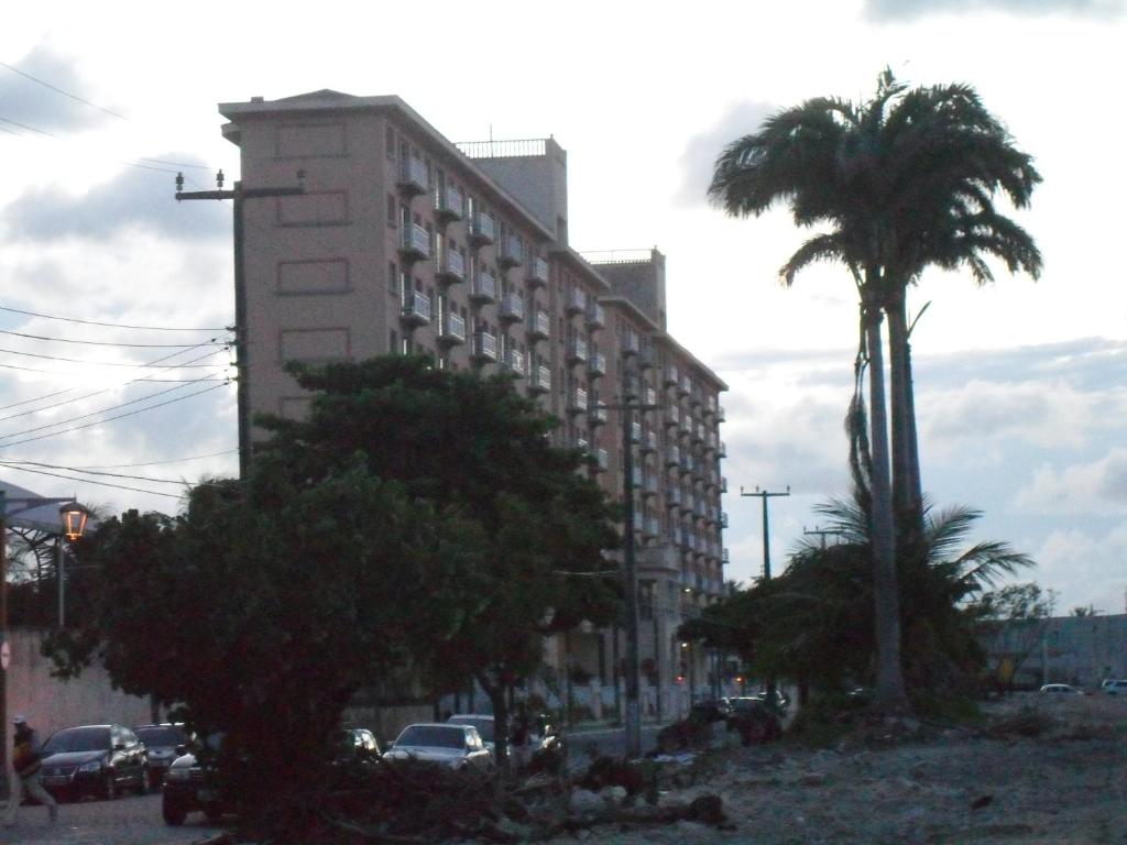 un grand bâtiment dans une rue avec un palmier dans l'établissement Suites Vila de Iracema, à Fortaleza