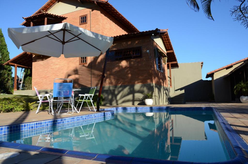 a swimming pool with a table and an umbrella at Casa em penedo in Penedo