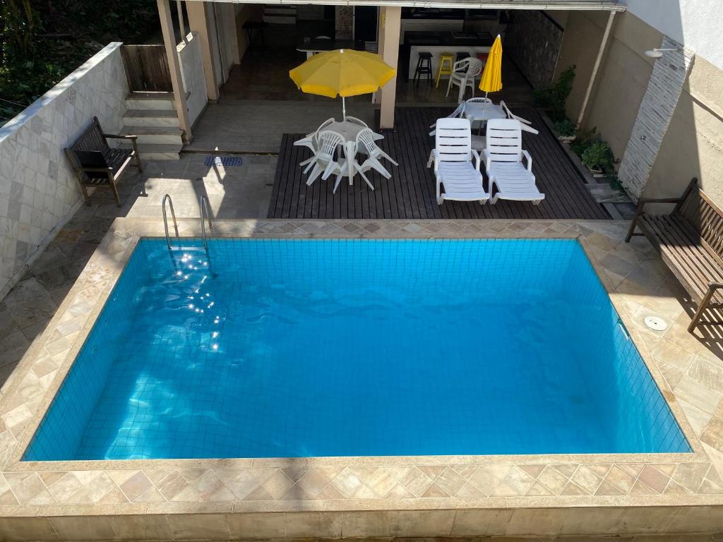 - une piscine avec des chaises, un parasol, une table et des chaises dans l'établissement Residencial Lúpulos, à Angra dos Reis