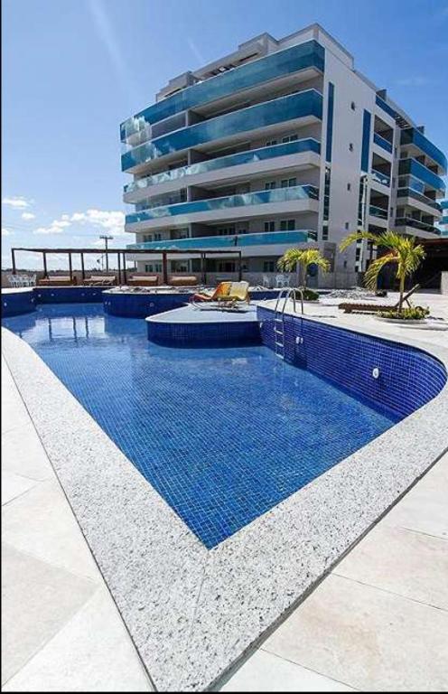 a swimming pool in front of a large building at Arraial do cabo in Arraial do Cabo