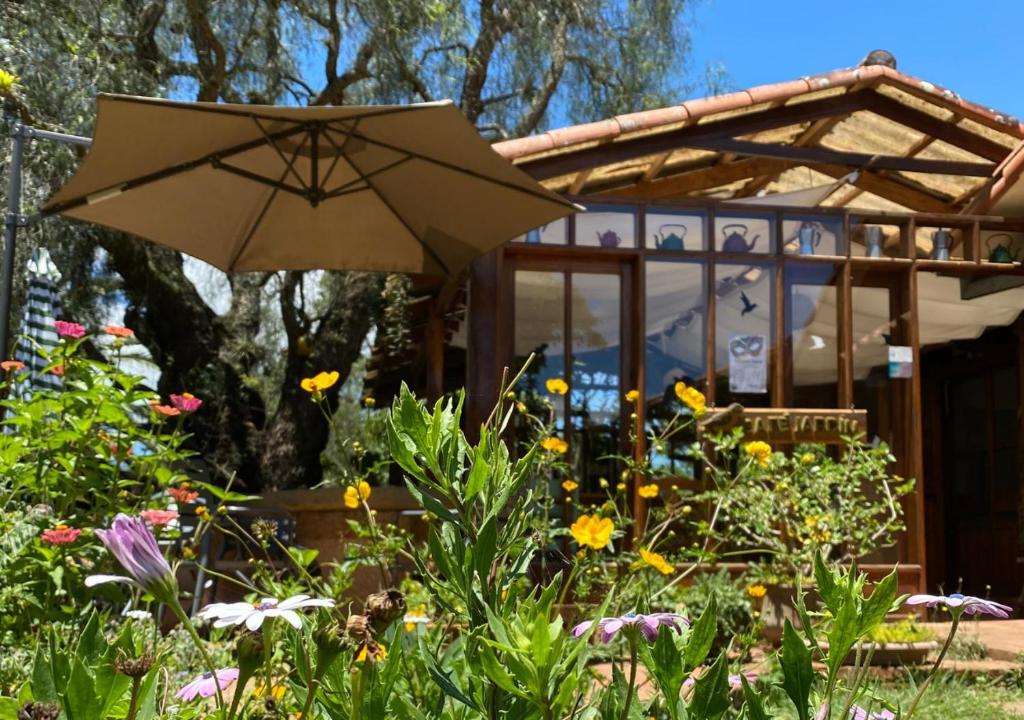 an umbrella in a garden in front of a house at Finca La Vispera in Samaipata