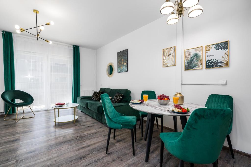 salon ze stołem i zielonymi krzesłami w obiekcie Sleepway Apartments- Garbary 100-46 w Poznaniu