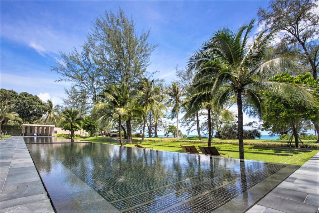 - une piscine à débordement dans une villa avec des palmiers dans l'établissement Luxury Oceanfront_pool access apartment, à Mai Khao Beach