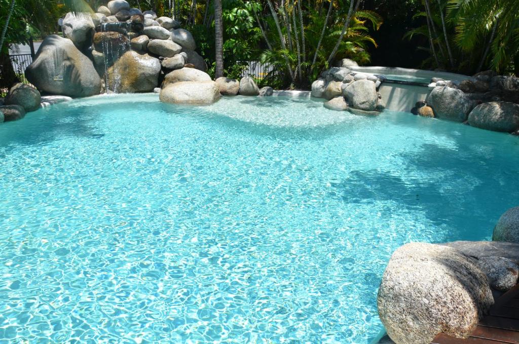 une grande piscine d'eau bleue avec des rochers dans l'établissement Beach Terraces, à Port Douglas